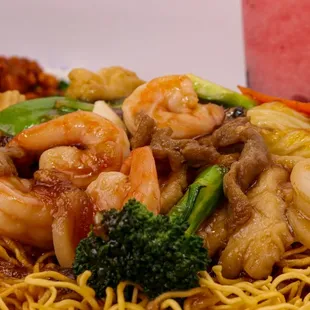 a plate of noodles with shrimp and broccoli