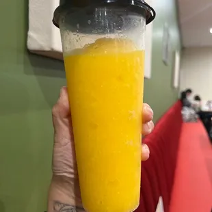 a person holding a cup of orange juice