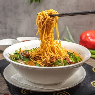 a bowl of noodles with chopsticks