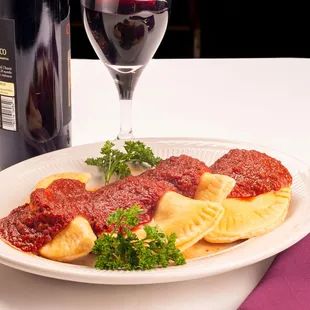 a plate of ravioli with a glass of wine
