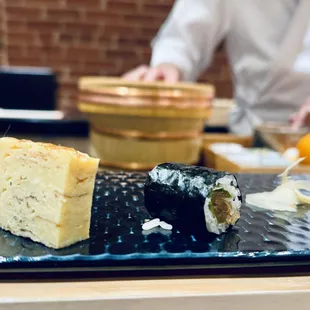 a plate of sushi with a man in the background