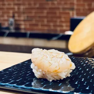 a piece of sushi on a black plate