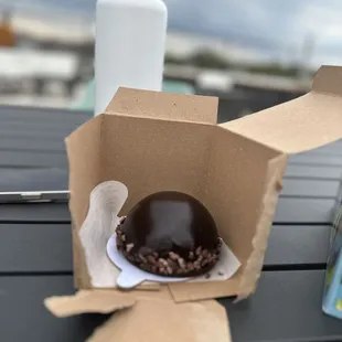 a chocolate covered donut in a box