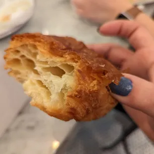 a person holding a pastry with a bite taken out of it