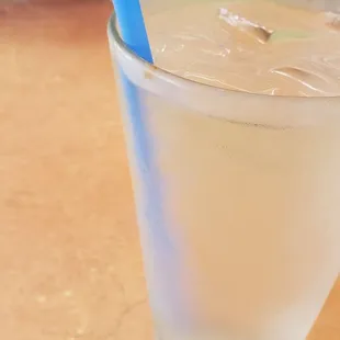 a glass of lemonade with a blue straw