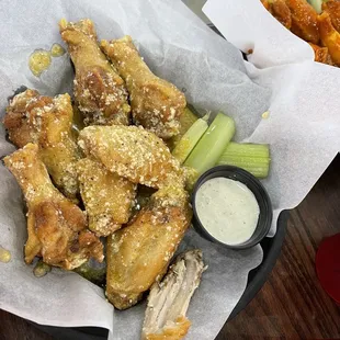 a basket of chicken wings with celery and ranch dressing