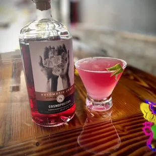 a pink cocktail and a bottle of gin