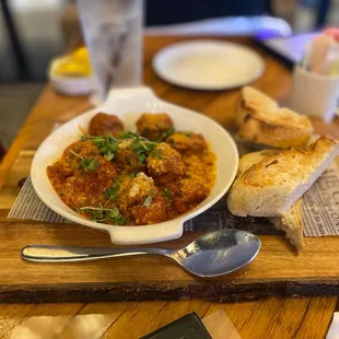 a bowl of stew and bread on a cutting board