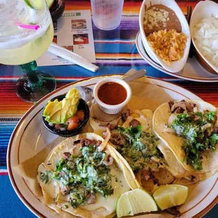 Asada Tacos w/ mucho cilantro and onions, avacado salad, rice and beans