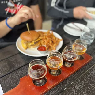 a tray of beer glasses and a burger