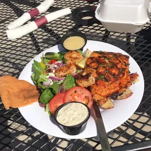 Salmon with three shrimp, a side of red potatoes and a Greek salad.