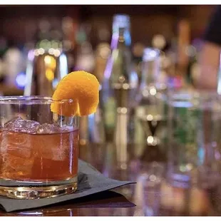 a drink in a glass with an orange garnish