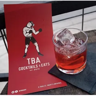 a glass of cocktail with ice on a table