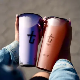 a person holding two coffee cups