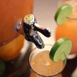 two glasses of orange juice with lime wedges