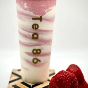 a glass of strawberry yogurt with a strawberries on a coaster