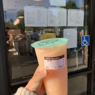 a hand holding a cup of iced tea