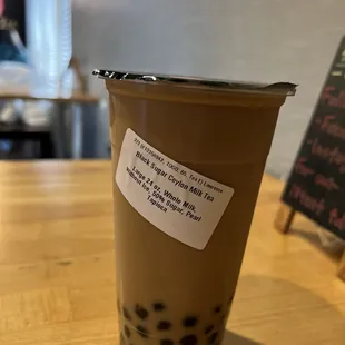 Black sugar Ceylon milk tea against a dingy wall