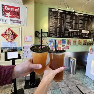 two people toasting drinks at a coffee shop