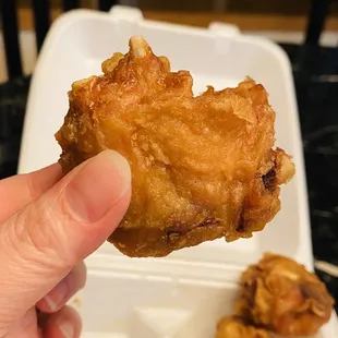 a hand holding a piece of fried chicken