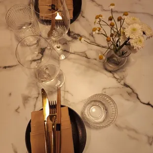 Place settings at the dining tables with gold flatware and nice disposable chopsticks