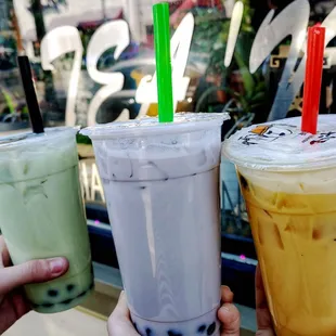 hand holding three different drinks