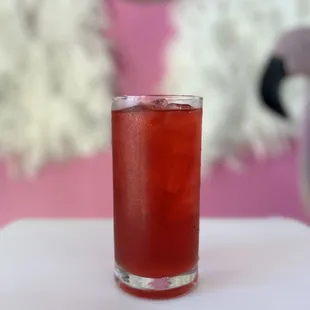 a glass of tea with a pink background