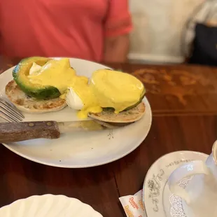 a plate of eggs benedict with avocado