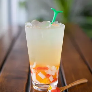 a closeup of a glass of tea and a spoon on a wooden table