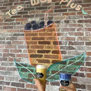 Mango Slush Milk Tea and Butterfly Latte against the artwork.