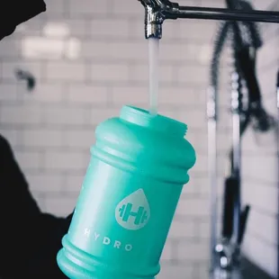 a person pouring tea into a teal cup