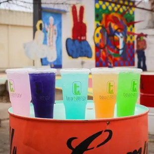 a row of plastic cups with colored drinks in them