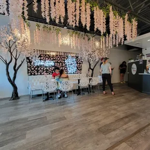 a woman standing in front of a table with flowers hanging from it