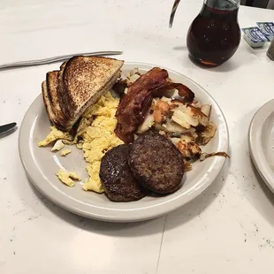 Scrambled eggs sausage bacon and some kind of potatoes