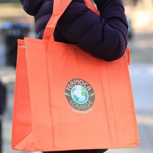 a woman carrying an orange shopping bag