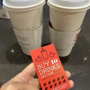 a hand holding a drink ticket and two cups of coffee