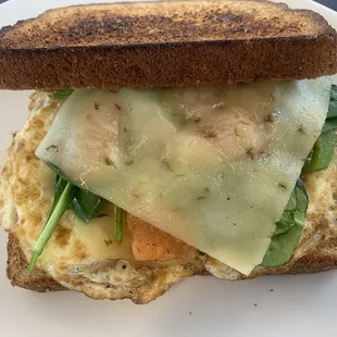Fried egg with veggies and cheese on wheat breakfast sandwich