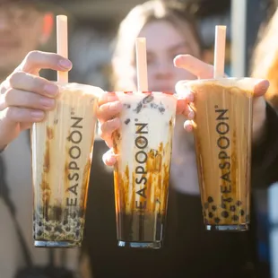 a group of people holding up iced teas