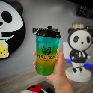 a hand holding a cup of bubble panda