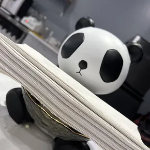 a panda bear holding a stack of paper