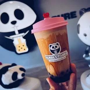 a hand holding a cup of bubble panda