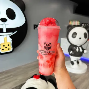 a hand holding a cup of bubble panda