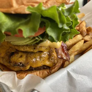 a hamburger with bacon, lettuce, tomato, cheese, and lettuce