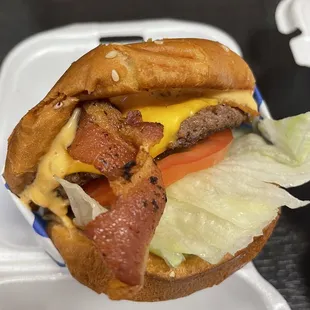 a hamburger with bacon, lettuce, tomato, and cheese