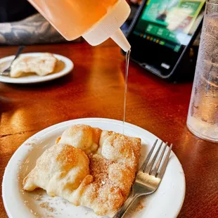 a plate of crepes being drizzled with syrup