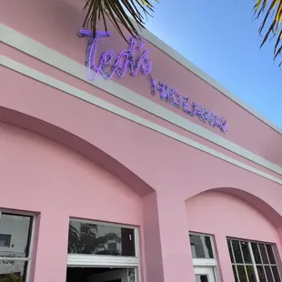 a pink building with a neon sign