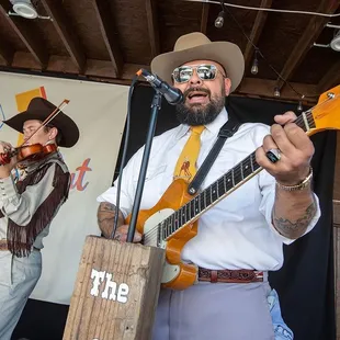a man with a beard playing a guitar and a violin