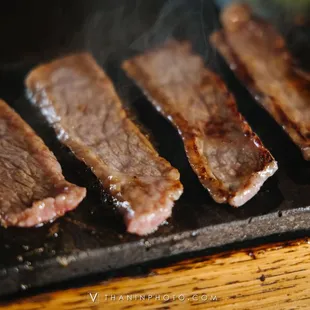 four pieces of meat being cooked on a grill