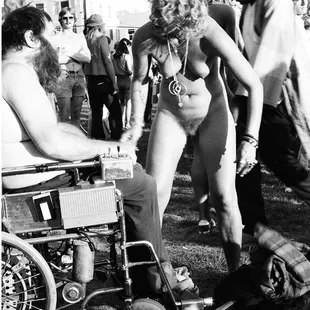 Pravda naked as usual wearing love beads. Pravda had just taken off the shirt of the man in wheelchair. This is in People's Park. Tom Brody