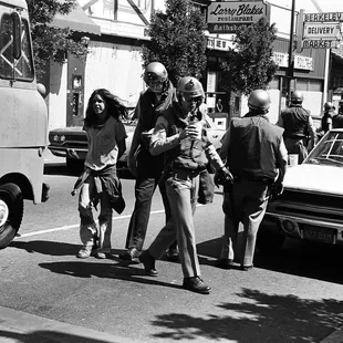 Riot police escorting bad boy to paddy wagon. You can see LARRY BLAKE'S restaurant.  Also, see car w window smashed by rioters. - Tom Brody